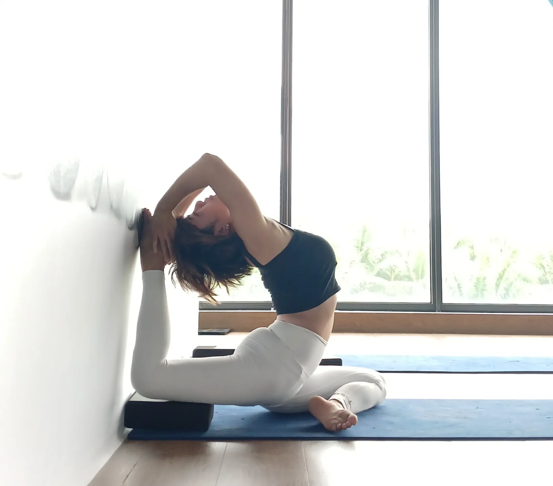 Student in a supported seated stretch by the studio window for gentle spinal decompression